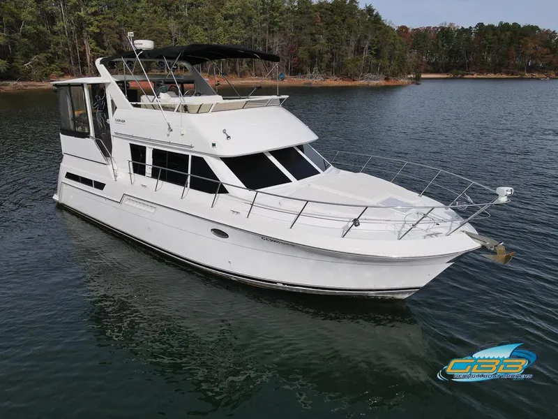 Slide: The Image of 1998 Carver 405 Aft Cabin yacht on a serene lake with forested shoreline. - 16