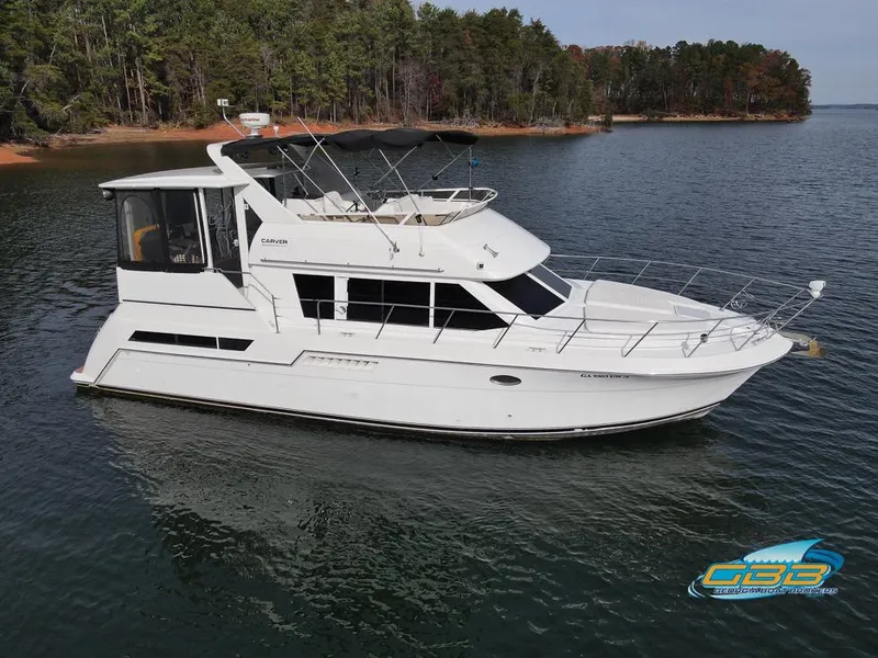 Slide: The Image of 1998 Carver 405 Aft Cabin yacht on a serene lake with forested shoreline. - 21