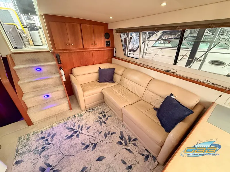 Slide: The Image of 1998 Carver 405 Aft Cabin interior with beige sofa, blue pillows, and floral rug. - 32