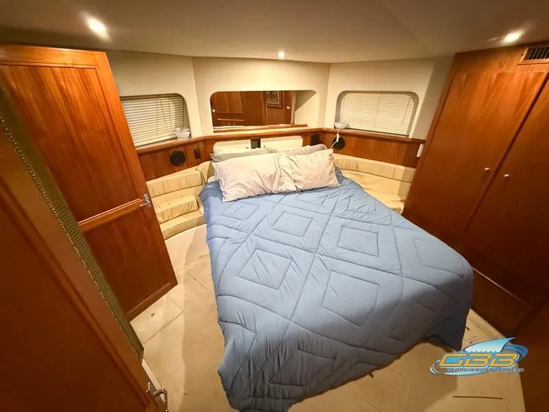 Slide: The Image of 1998 Carver 405 Aft Cabin bedroom with blue bedding and wooden cabinetry. - 36