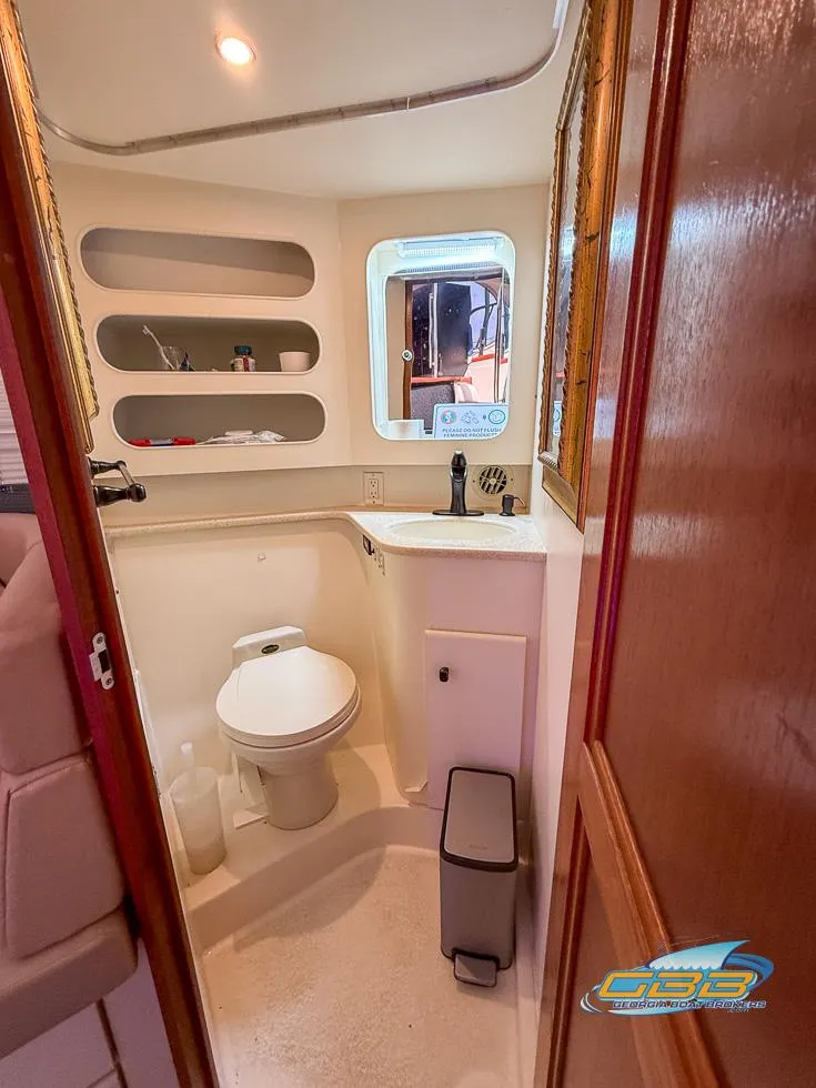 Slide: The Image of 1998 Carver 405 Aft Cabin bathroom with toilet, sink, and storage shelves. - 45