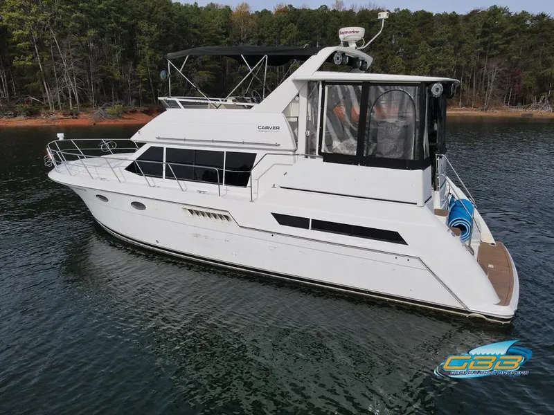 Slide: The Image of 1998 Carver 405 Aft Cabin yacht on calm water, surrounded by trees. - 10
