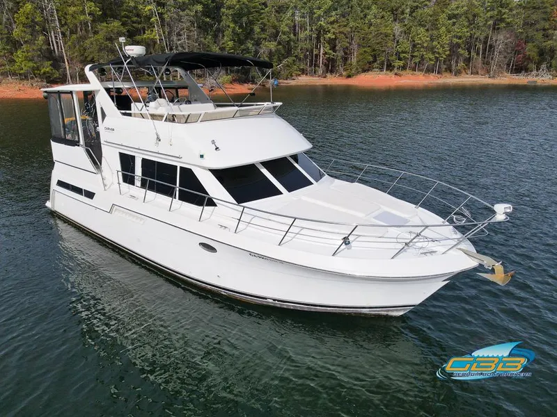 Slide: The Image of 1998 Carver 405 Aft Cabin yacht on a serene lake with forested shoreline. - 20