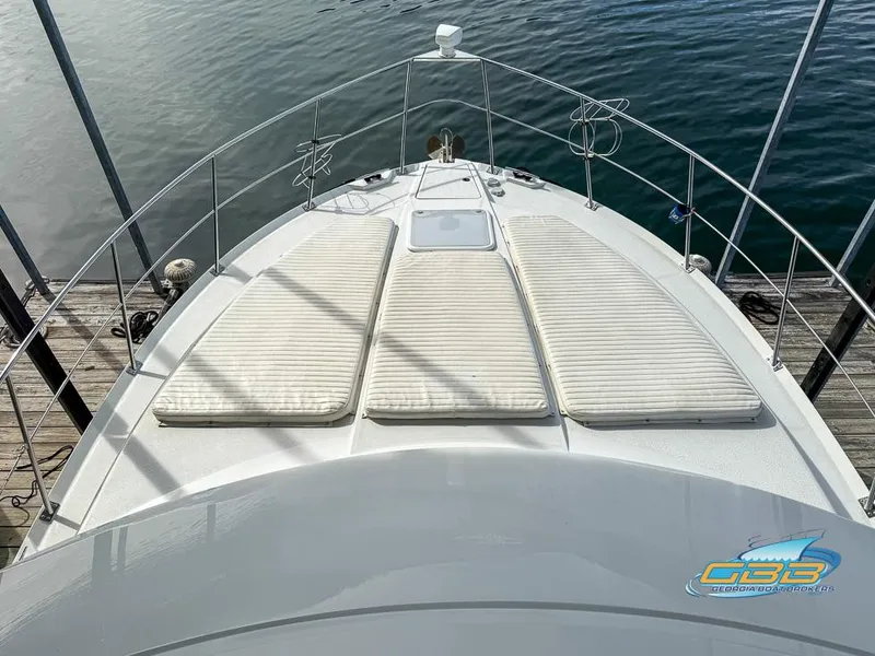 Slide: The Image of 1998 Carver 405 Aft Cabin yacht with sun pads on deck, docked by the water. - 28