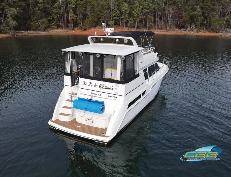 Slide: The Image of 1998 Carver 405 Aft Cabin yacht on serene lake with forest backdrop. - 3