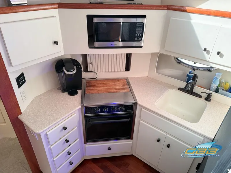 Slide: The Image of 1998 Carver 405 Aft Cabin kitchen with microwave, stove, and sink. - 38