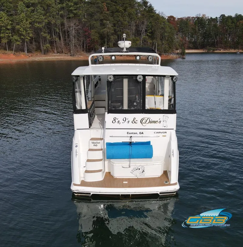 Slide: The Image of 1998 Carver 405 Aft Cabin boat on a serene lake with forested shoreline. - 4