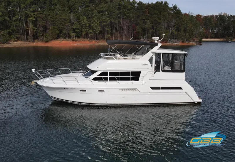 Slide: The Image of 1998 Carver 405 Aft Cabin yacht on serene lake with forested shoreline. - 5