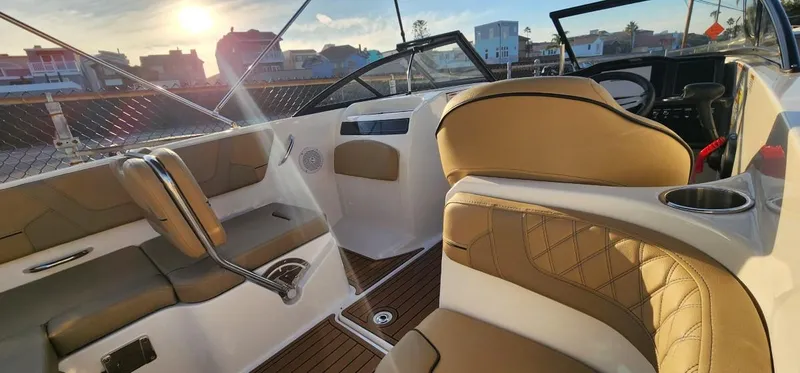 Slide: The Image of 2024 Bayliner VR6 Bowrider OB interior with tan seating and steering wheel, sunset view. - 26