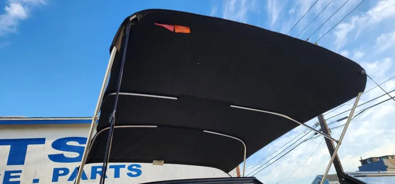 Slide: The Image of 2024 Bayliner VR6 Bowrider OB with black bimini top against blue sky. - 32