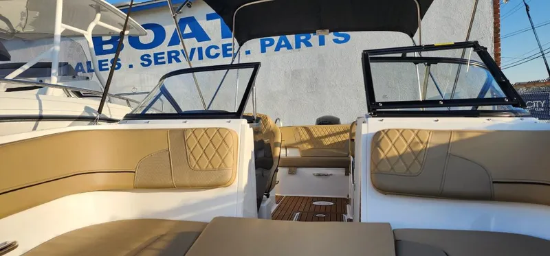 Slide: The Image of 2024 Bayliner VR6 Bowrider OB interior with tan seating, near boat sales and service sign. - 39