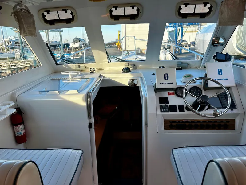 Slide: The Image of 2000 Mainship Pilot 30 Sedan cockpit with steering wheel, navigation equipment, and marina view. - 12