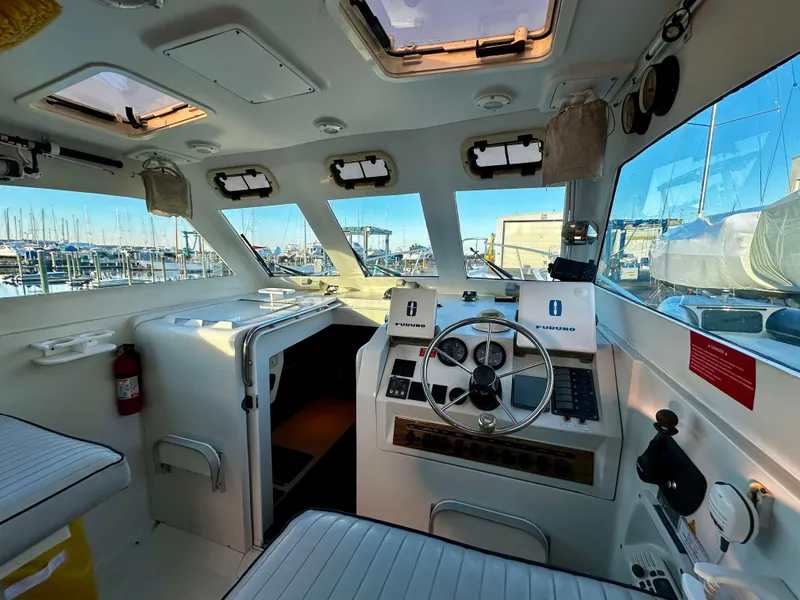 Slide: The Image of Interior of 2000 Mainship Pilot 30 Sedan boat, featuring helm and seating area. - 13