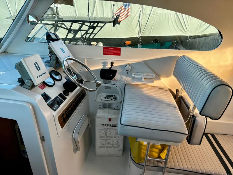 Slide: The Image of 2000 Mainship Pilot 30 Sedan helm with steering wheel, navigation equipment, and cushioned seating. - 14