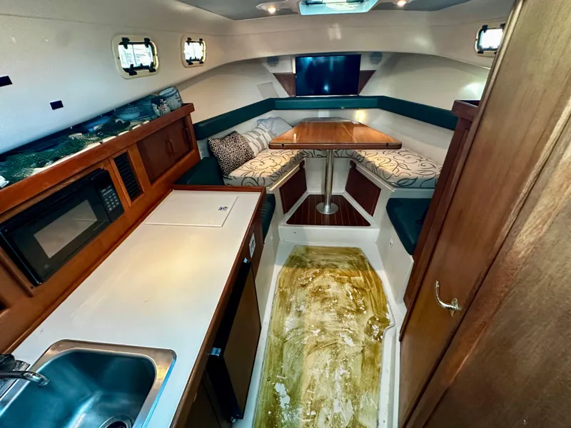 Slide: The Image of 2000 Mainship Pilot 30 Sedan interior with kitchenette, seating, and dining area. - 16