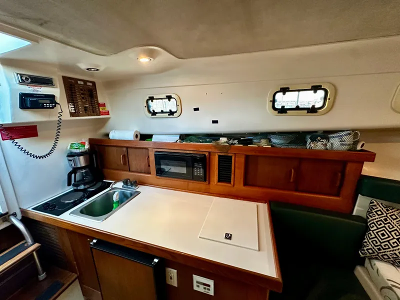 Slide: The Image of 2000 Mainship Pilot 30 Sedan interior with kitchenette, microwave, and sink. - 18