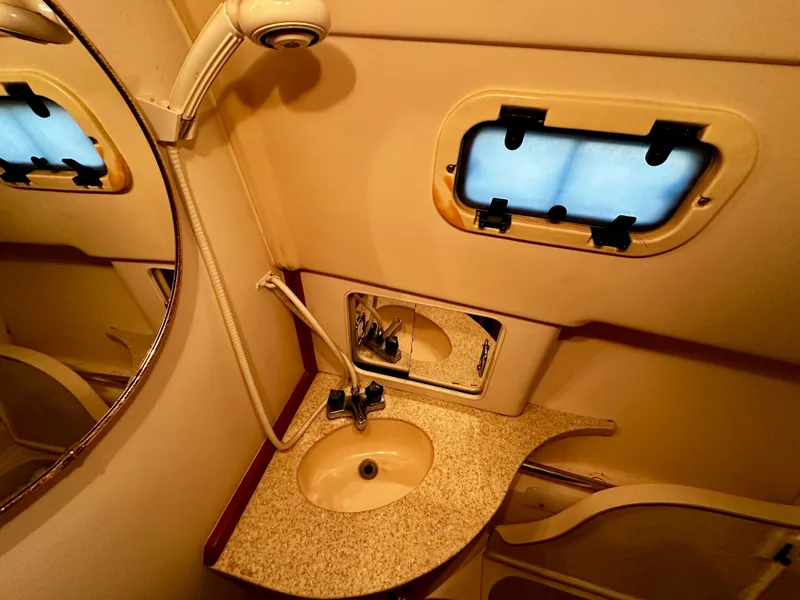 Slide: The Image of 2000 Mainship Pilot 30 Sedan bathroom with sink, mirror, and porthole window. - 23