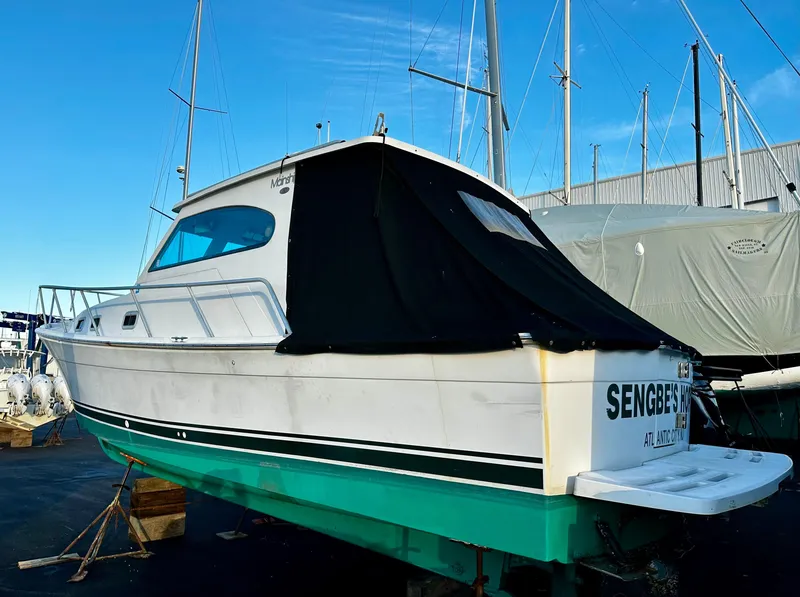 Slide: The Image of 2000 Mainship Pilot 30 Sedan boat on dry dock with black cover. - 28