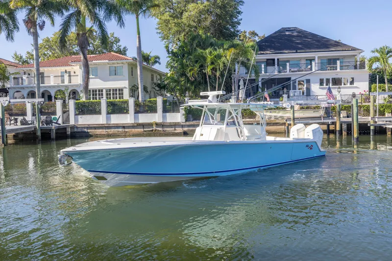 Slide: The Image of 2022 SeaVee 390Z boat docked near waterfront homes, surrounded by palm trees. - 2