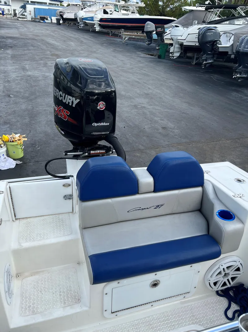 Slide: The Image of 2016 Concept 27' CC boat with Mercury OptiMax engine, blue seating, and docked boats in background. - 9