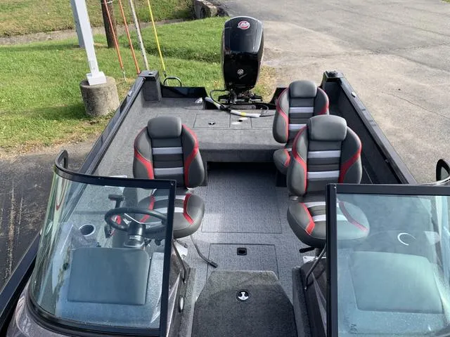 Slide: The Image of 2024 Ranger VS1882 boat interior with four seats and motor, parked on pavement. - 5