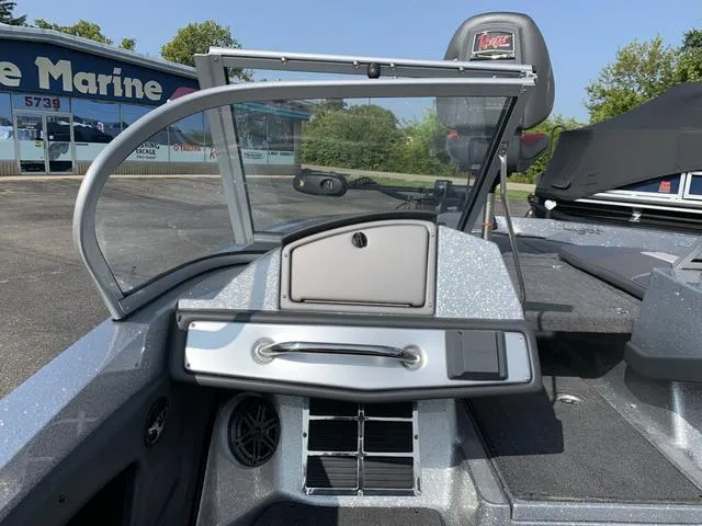 Slide: The Image of 2025 Ranger 212LS boat interior with windshield and dashboard, parked near a marine shop. - 5