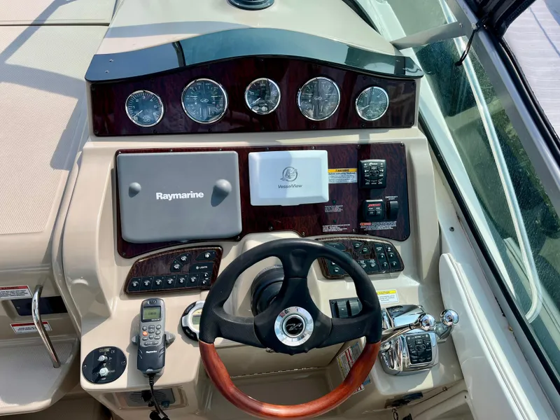 Slide: The Image of 2009 Sea Ray 310 Sundancer helm with Raymarine navigation and wood-accented steering wheel. - 15