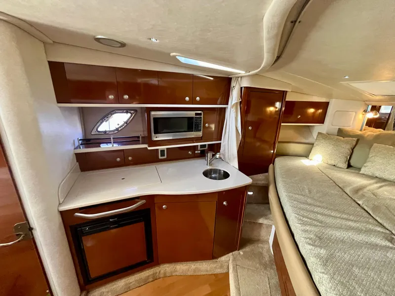 Slide: The Image of 2009 Sea Ray 310 Sundancer interior with kitchenette, microwave, sink, and cozy sleeping area. - 17