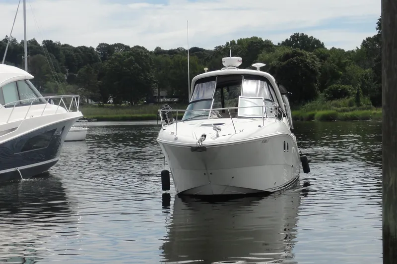 Slide: The Image of 2009 Sea Ray 310 Sundancer yacht docked on calm water, surrounded by lush greenery. - 25
