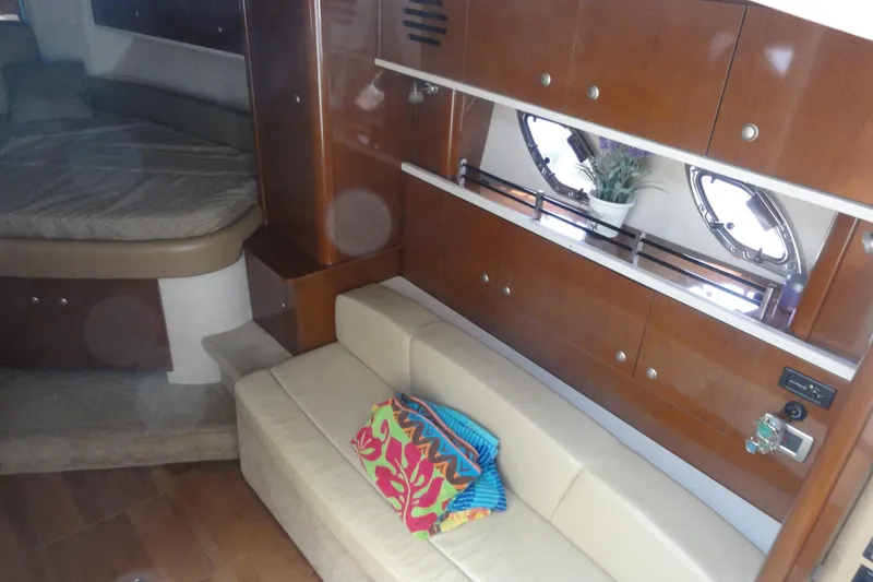 Slide: The Image of 2009 Sea Ray 310 Sundancer interior with beige seating, wooden cabinets, and decorative accents. - 36