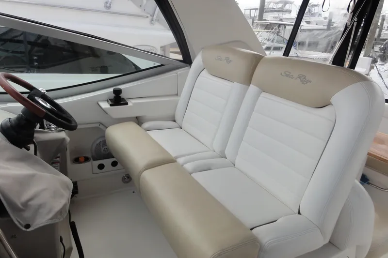 Slide: The Image of 2009 Sea Ray 310 Sundancer cockpit with white and beige seating, steering wheel, and controls. - 44