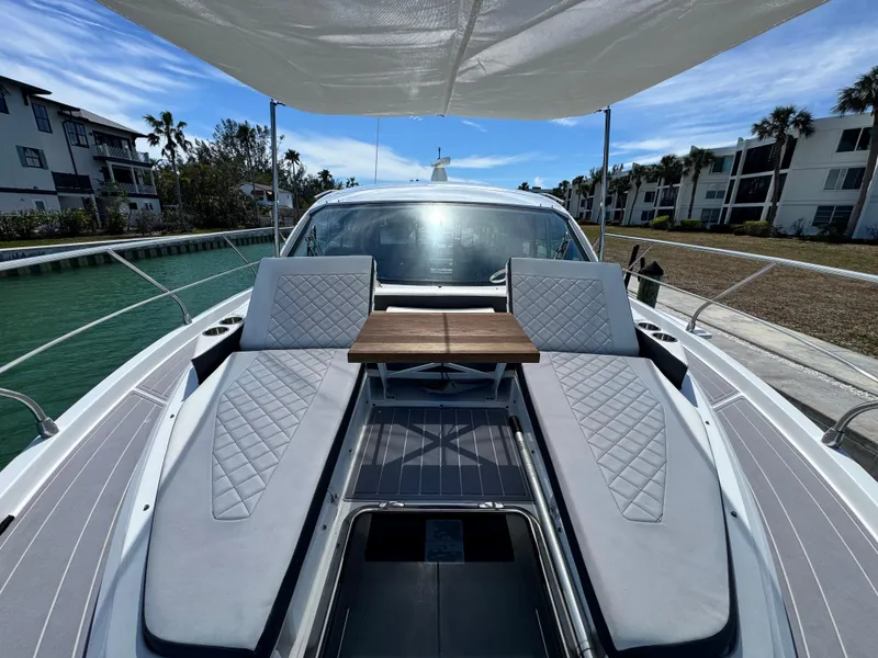 Slide: The Image of 2019 Cruisers Yachts 42 Cantius with sun loungers and table on deck, docked by waterfront homes. - 6