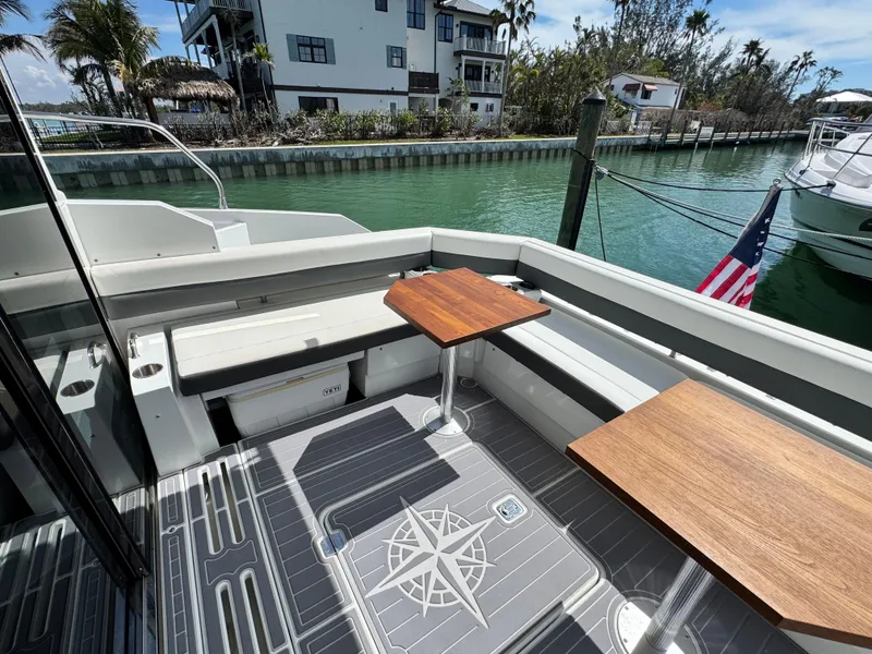 Slide: The Image of 2019 Cruisers Yachts 42 Cantius deck with wooden tables, docked by a canal. - 8