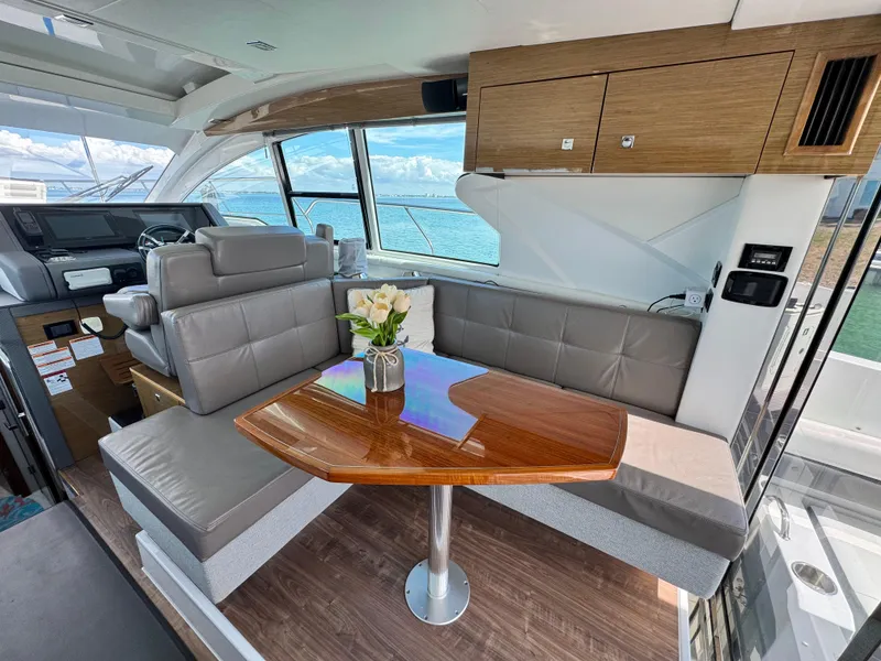 Slide: The Image of 2019 Cruisers Yachts 42 Cantius interior with elegant seating and wooden table, overlooking the ocean. - 13