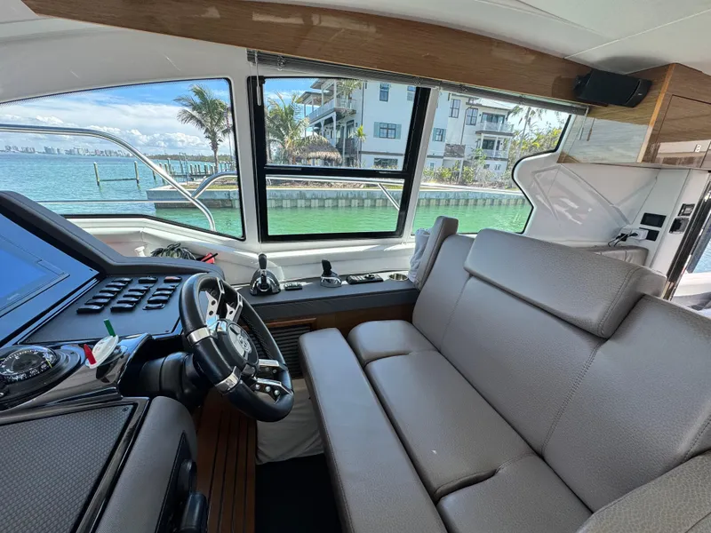 Slide: The Image of Interior of 2019 Cruisers Yachts 42 Cantius with helm and seating, overlooking waterfront. - 17