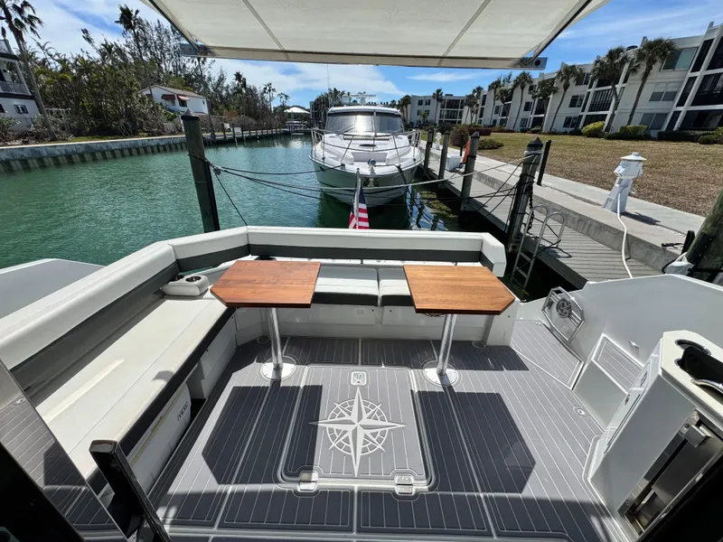 Slide: The Image of 2019 Cruisers Yachts 42 Cantius docked, featuring spacious outdoor seating and dual tables. - 9