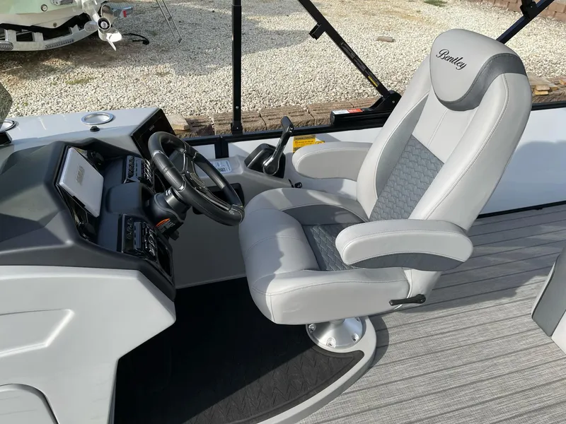 Slide: The Image of 2025 Bentley Pontoons Elite 223 Swingback captain's chair and helm, featuring sleek design and controls. - 15