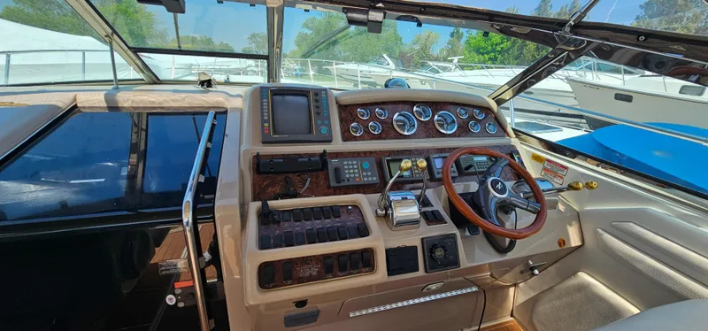 Slide: The Image of 1999 Sea Ray 400 Express Cruiser helm with gauges, controls, and wooden steering wheel. - 14