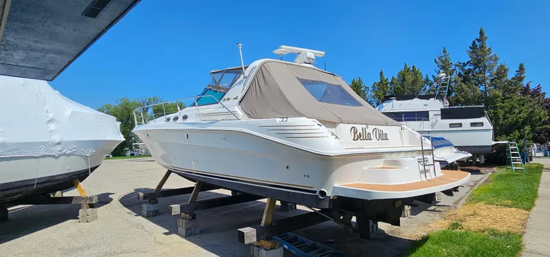 Slide: The Image of 1999 Sea Ray 400 Express Cruiser on stands, outdoors, under clear blue sky. - 2