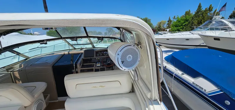 Slide: The Image of 1999 Sea Ray 400 Express Cruiser interior with helm, seating, and speaker, docked under clear blue sky. - 22