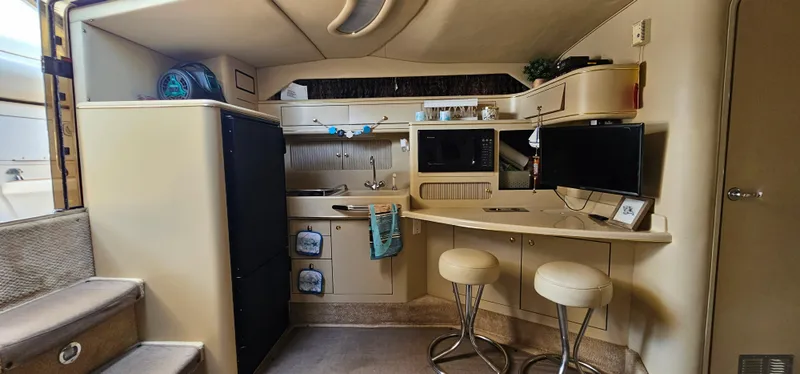 Slide: The Image of Interior of 1999 Sea Ray 400 Express Cruiser with kitchenette and seating area. - 29
