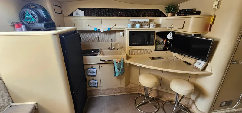 Slide: The Image of 1999 Sea Ray 400 Express Cruiser interior with kitchen, seating, and modern amenities. - 32