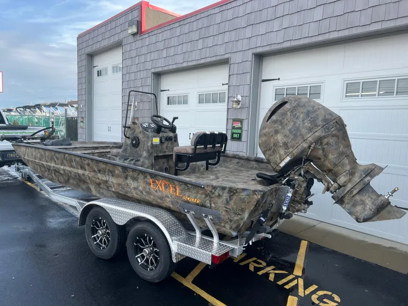 Slide: The Image of Excel 2072 Stalker SC 2025 boat on trailer, camo design, parked outside garage. - 3