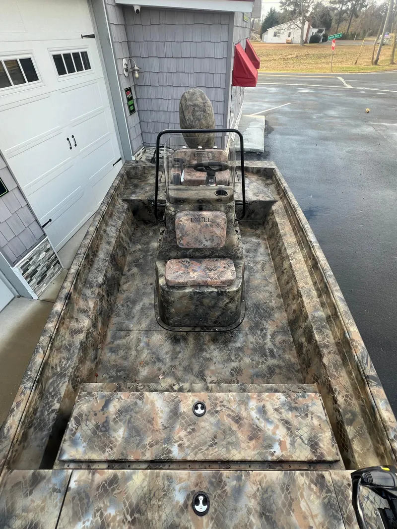 Slide: The Image of Camouflage-patterned 2025 Excel 2072 Stalker SC boat parked near a garage. - 5