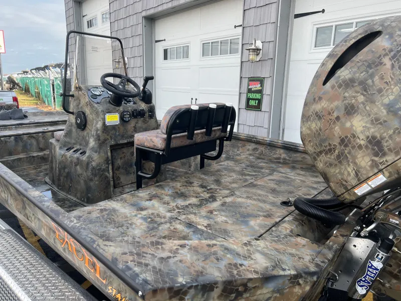 Slide: The Image of 2025 Excel 2072 Stalker SC boat with camouflage design, parked near garage doors. - 9
