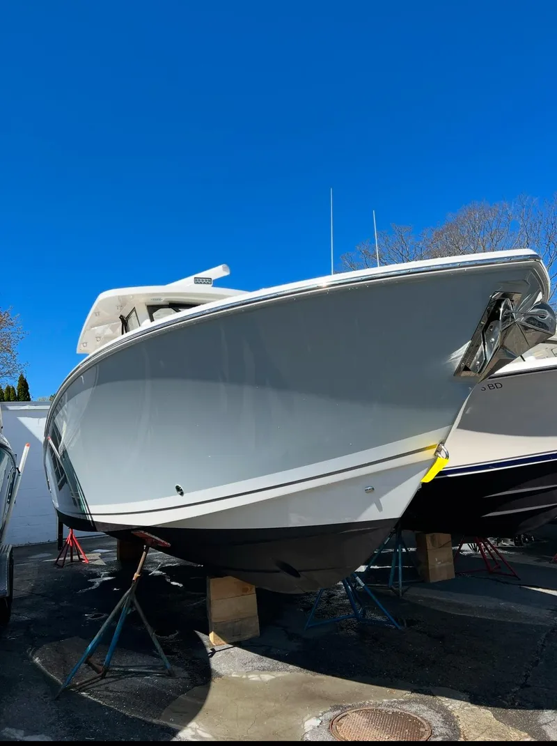 Slide: The Image of 2021 Pursuit S 328 Sport boat displayed outdoors under clear blue sky. - 10