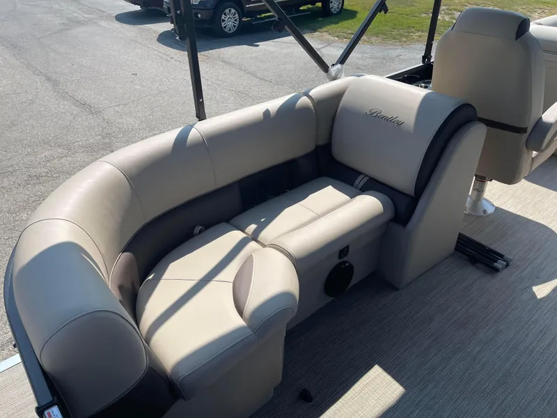 Slide: The Image of 2024 Bentley Pontoons Legacy 200 Navigator interior seating, beige upholstery, outdoor setting. - 24