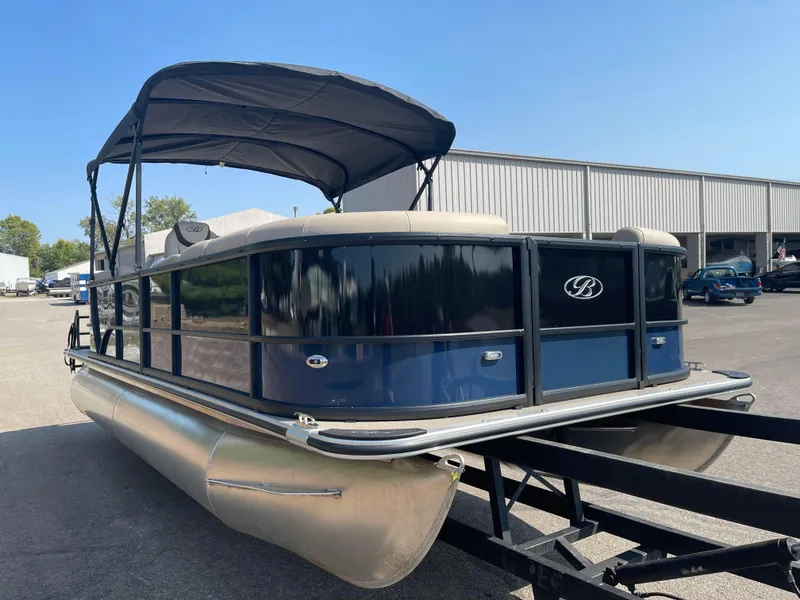 Slide: The Image of 2024 Bentley Pontoons Legacy 200 Navigator on trailer, blue exterior, parked outdoors. - 6