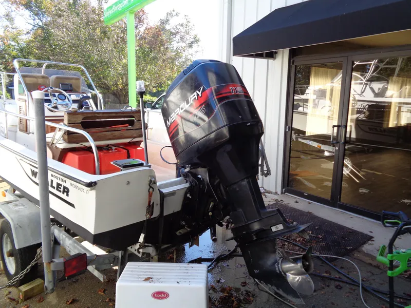 Slide: The Image of 1980 Boston Whaler 17 Montauk boat with Mercury outboard motor, parked near a building. - 12