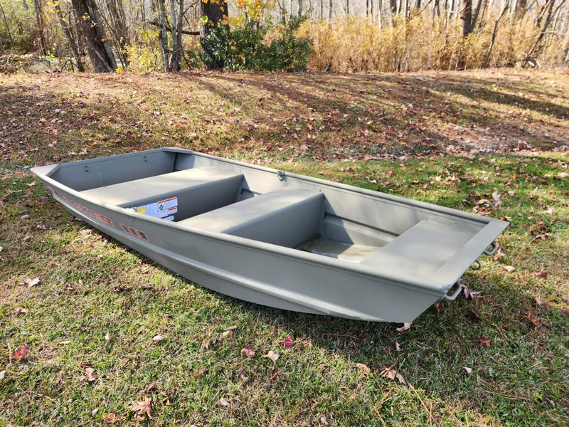 Slide: The Image of 2025 Tracker Grizzly 1036 Utility boat on grassy area, surrounded by autumn trees. - 2